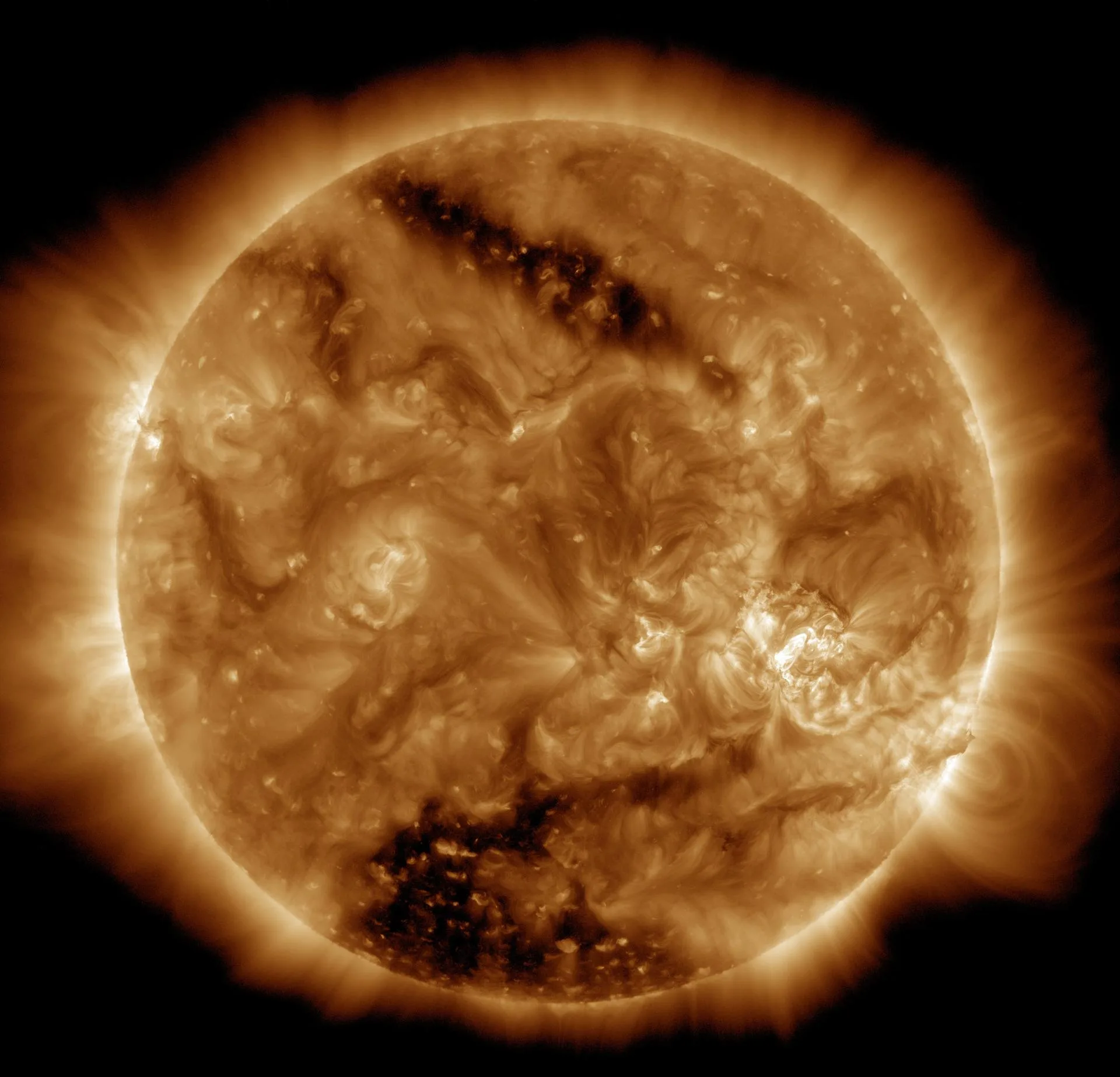 SDO'nun 16 Mart 2015'te görüntülediği iki koronal delik (koyu bölgeler). Güney kutbuna yakın büyük delik Güneş yüzeyinin tahminen %6–8'ini kaplıyor. Koronal delikler, hızlı Güneş rüzgârının kaynağıdır.