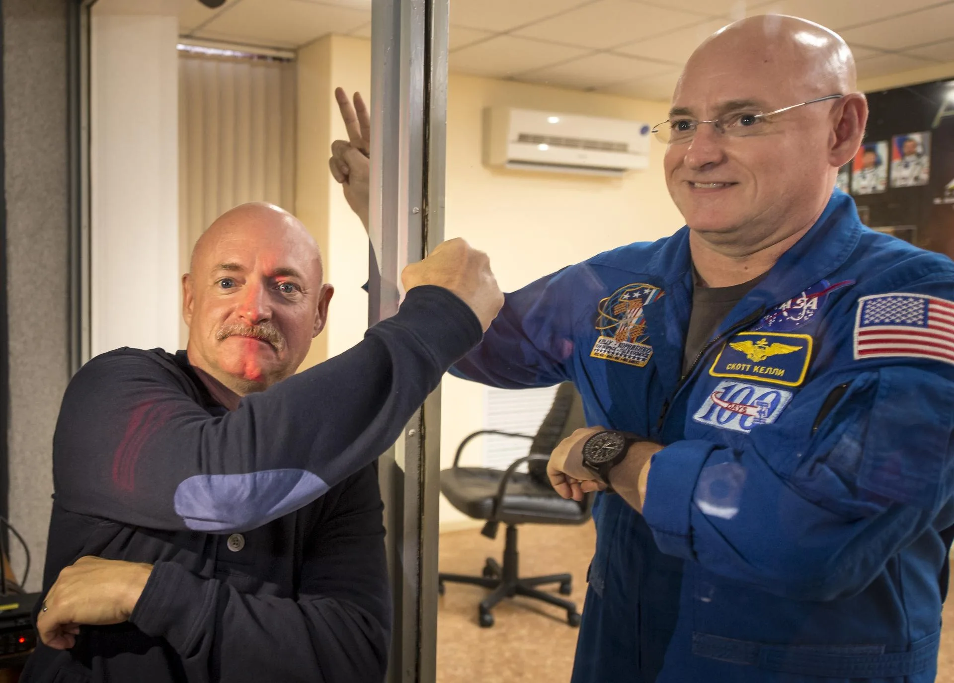 Astronot Scott Kelly (camın arkasında) ve ikiz kardeşi Mark Kelly, Mart 2015'te Baykonur'da. Scott Kelly'nin yaklaşık bir yıllık uzay istasyonu görevi, gerçek bir 'ikiz' karşılaştırmasına dönüştü.