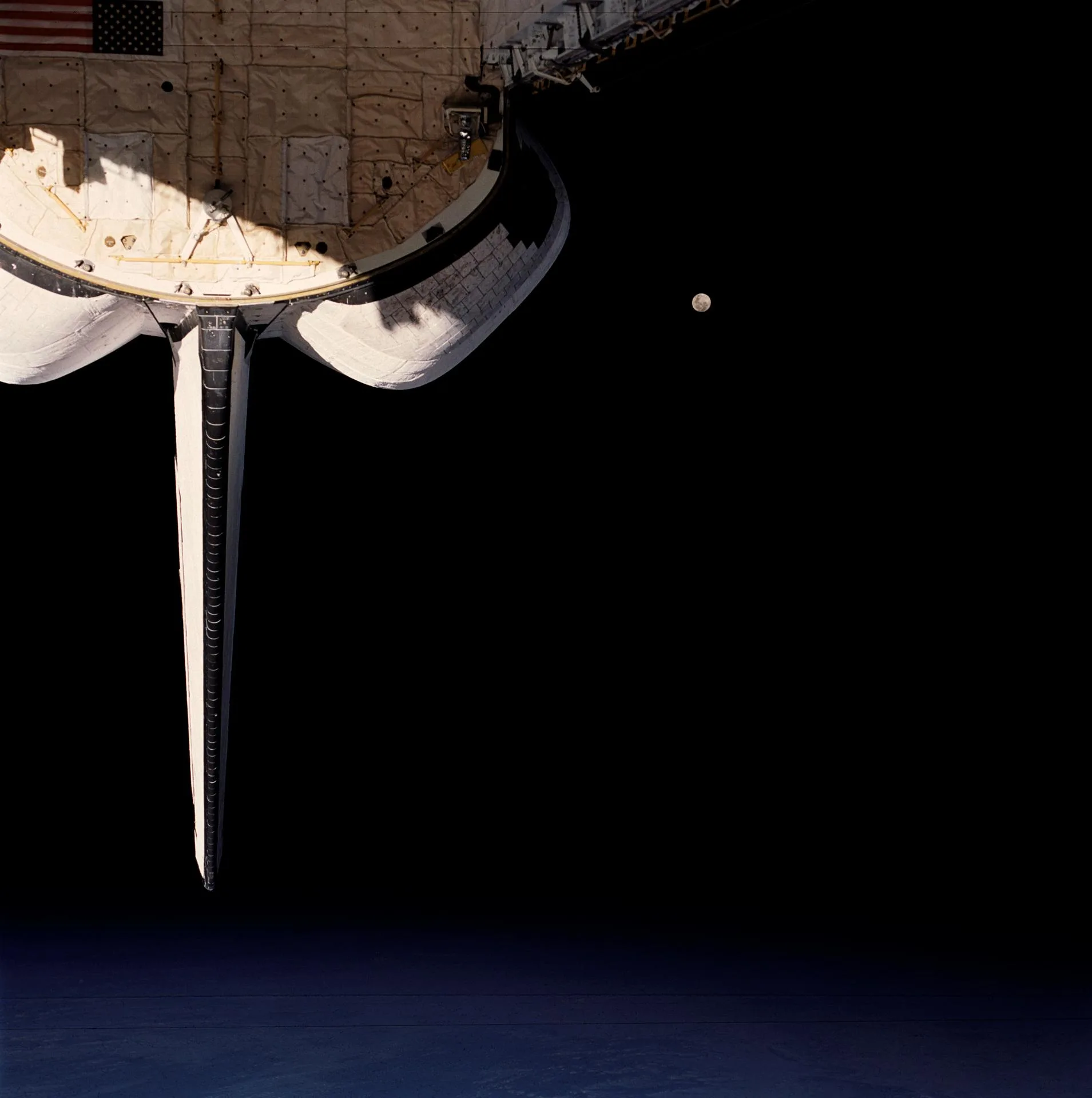 Discovery mekiğinin kargo bölümü, okyanus üzerindeki bulutlar ve uzayın karanlığında dolunay (STS-53, Aralık 1992).