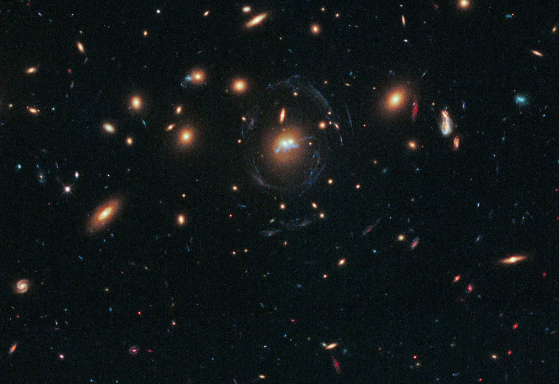 Hubble'ın görüntülediği SDSS J1531+3414 gökada kümesi: kümenin güçlü kütleçekimi, arkadaki gökadaların ışığını mavi yaylar hâlinde büküyor