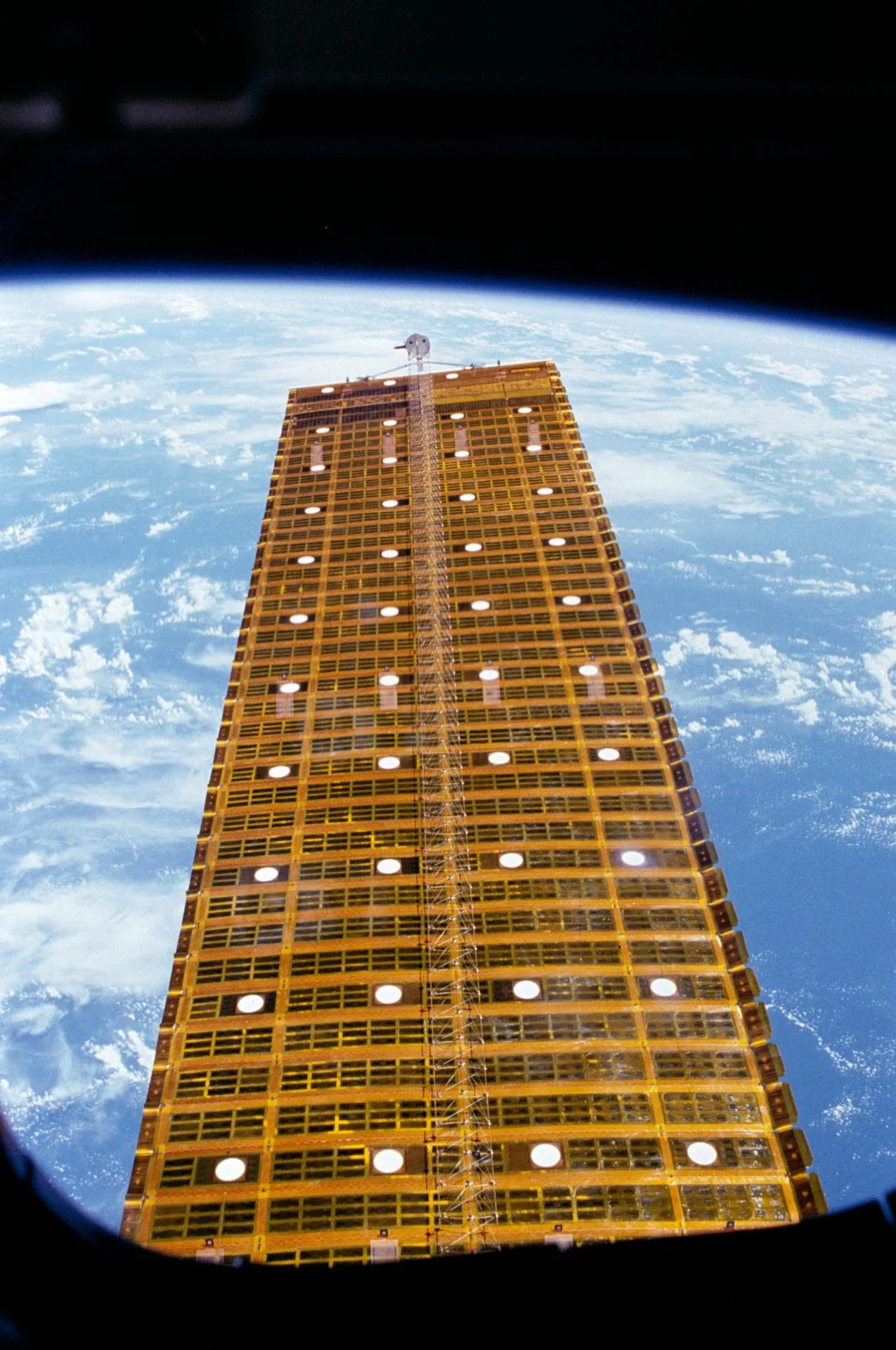 STS-41-D görevinde açılan deneysel OAST-1 güneş paneli, mekiğin penceresinden görülüyor (1984).
