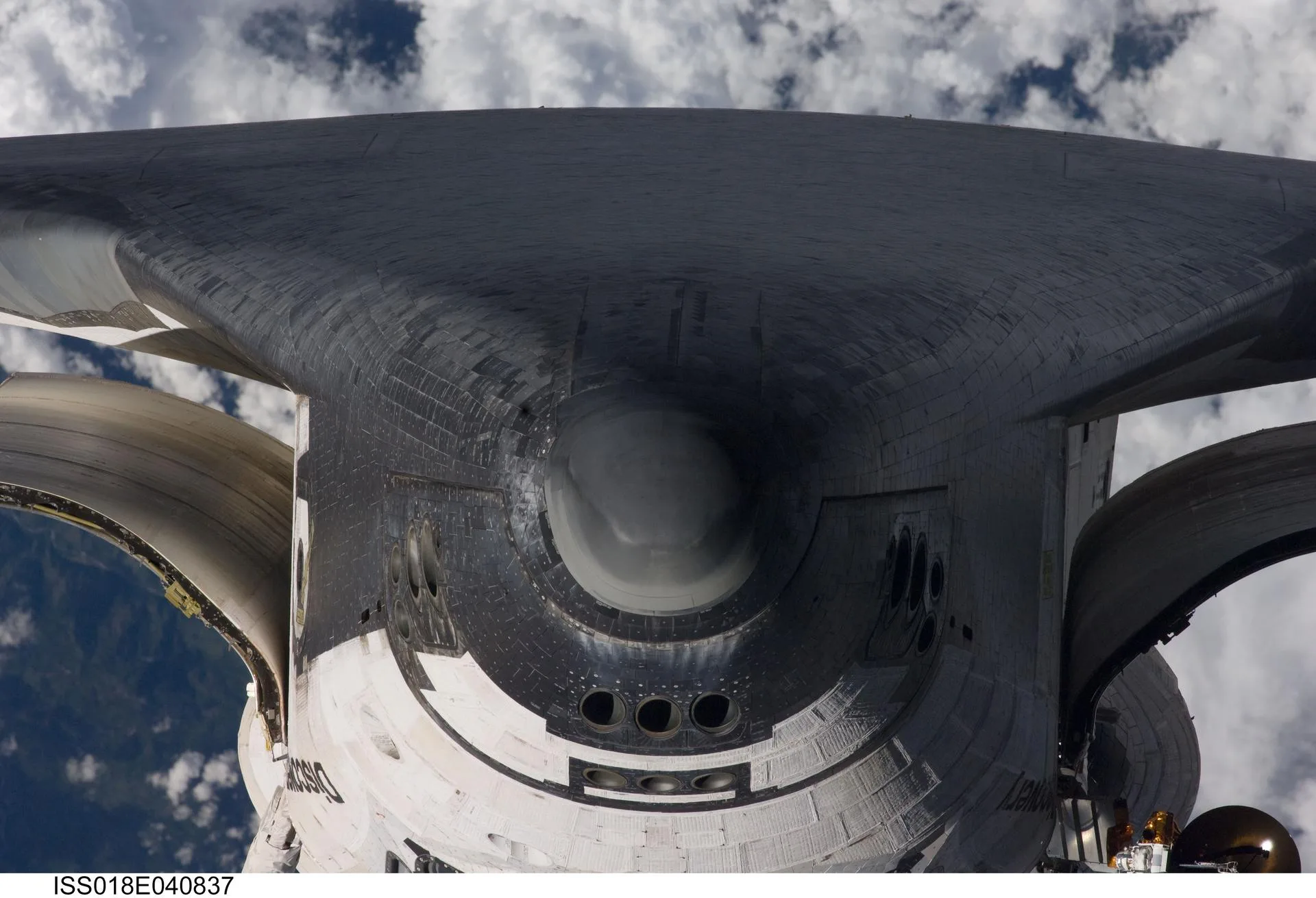 Uzay Mekiği Discovery, Mart 2009'daki STS-119 görevinde istasyona kenetlenmeden önce yaptığı takla manevrası sırasında. Burnun altındaki siyah karolar, atmosfere dönüşte aracı ısıdan koruyan kalkanın parçası.