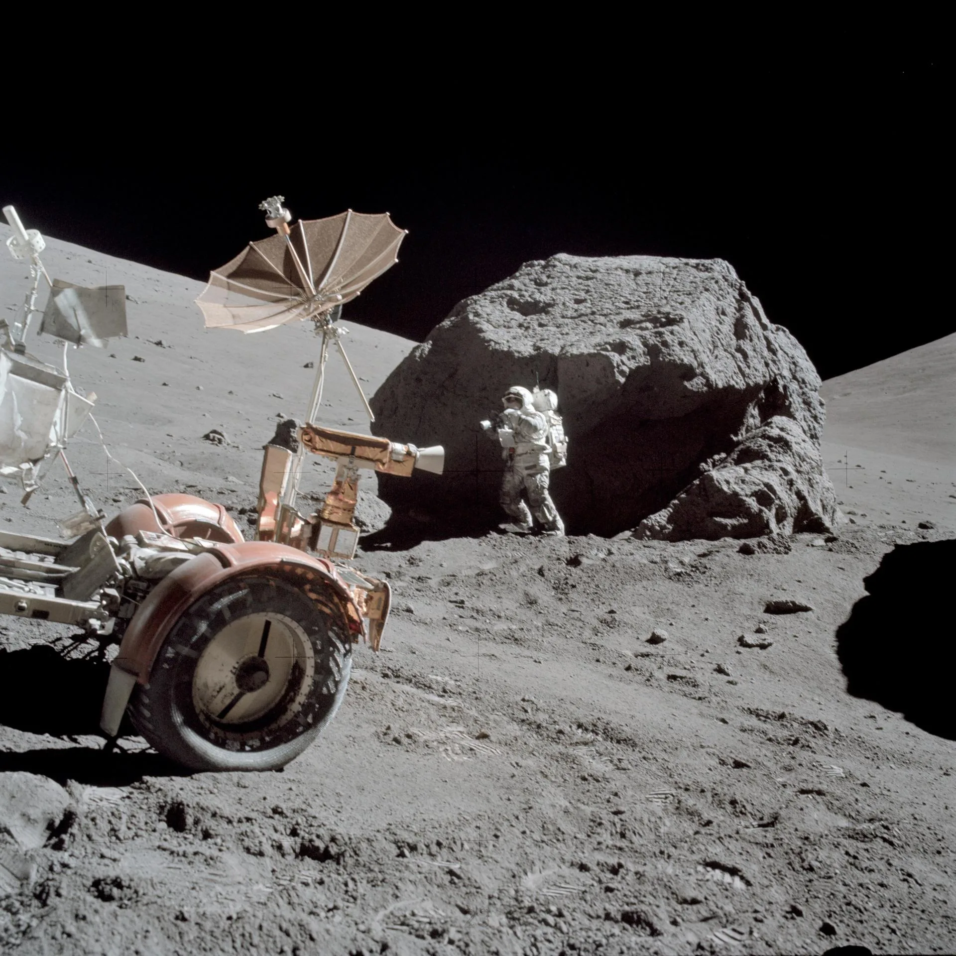 Apollo 17, 13 Aralık 1972: Harrison Schmitt, Taurus-Littrow vadisinde dev bir kaya parçasının yanında çalışıyor; solda Ay aracı görülüyor.