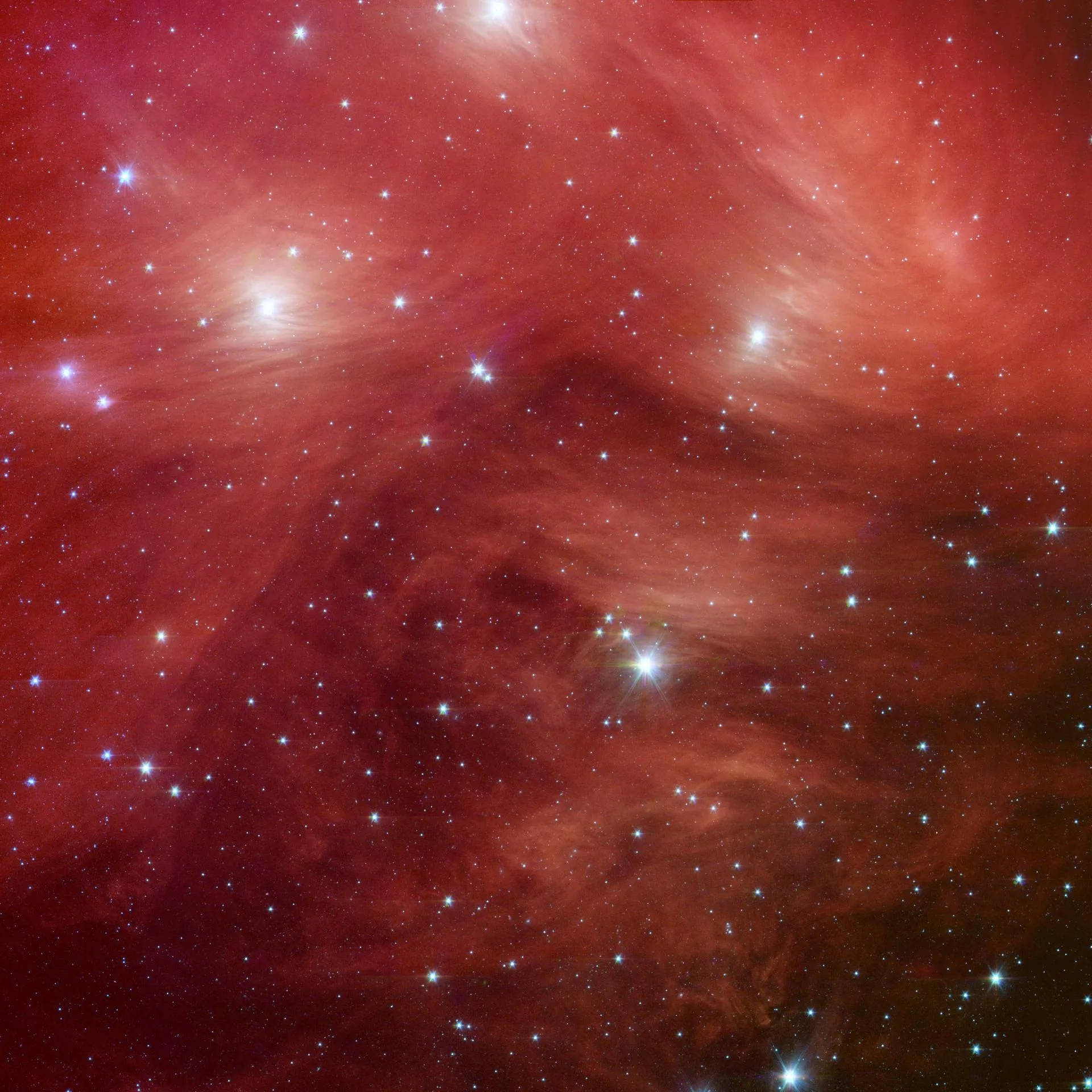Ülker (Pleiades) kümesi Spitzer Uzay Teleskobu'nun kızılötesi bakışıyla. Genç ve sıcak yıldızlar, içinden doğdukları toz bulutunu aydınlatıyor.